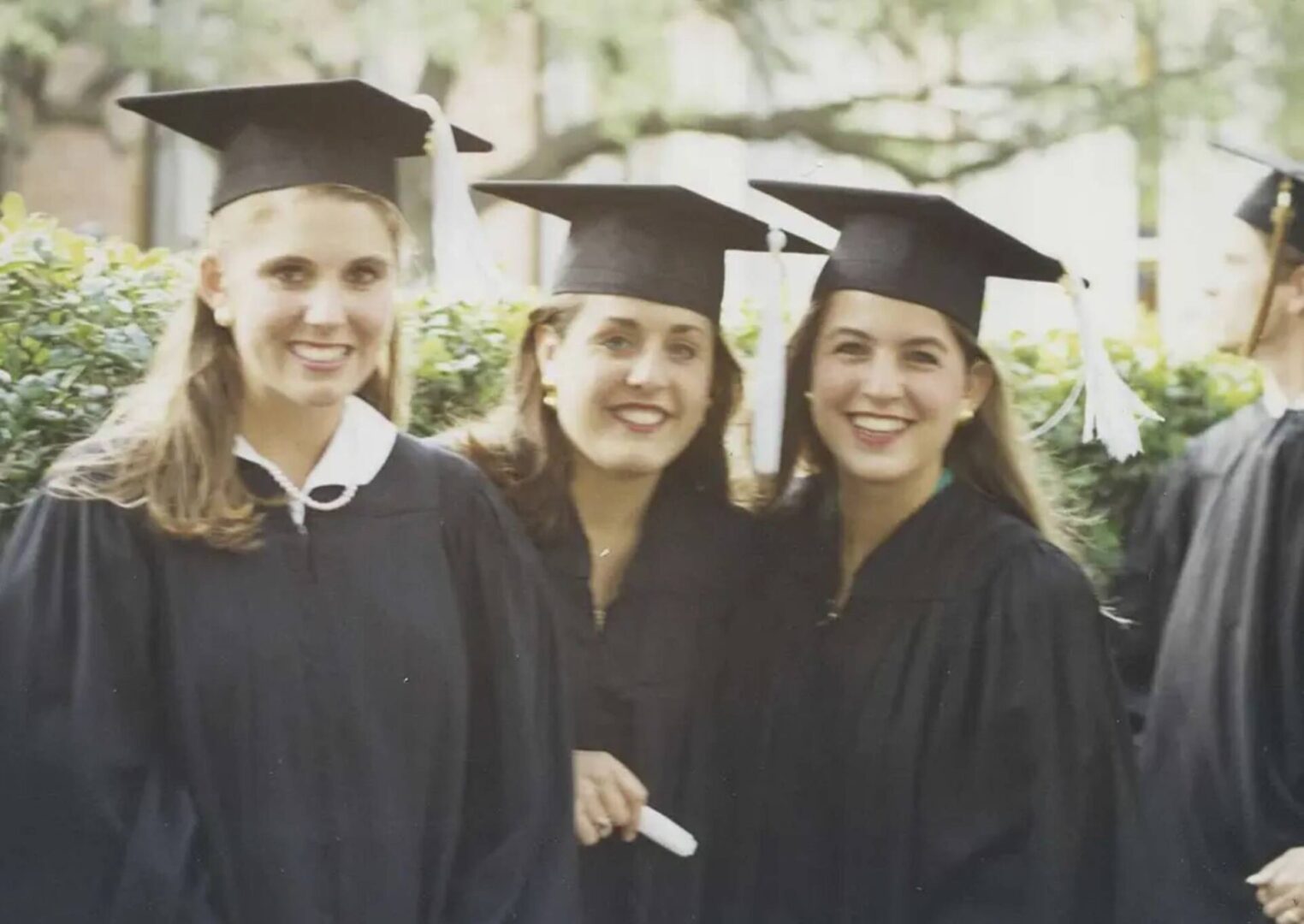 Three young women in graduation gowns and caps.